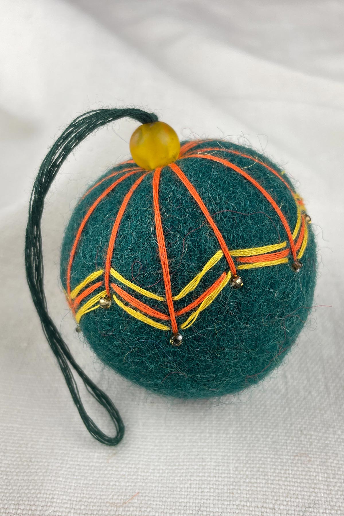 Close-up of beads on felt bauble in teal green