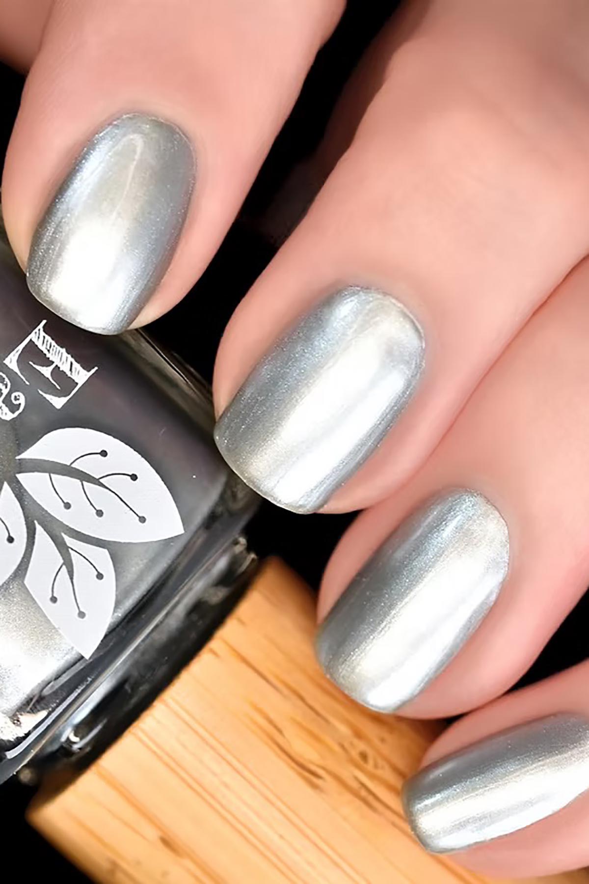 Earthy Theia Nail Polish bottle bamboo lid metallic tone lifestyle close-up