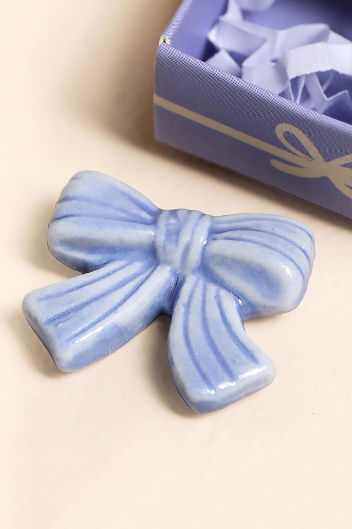 Ceramic bow token displayed outside matchbox