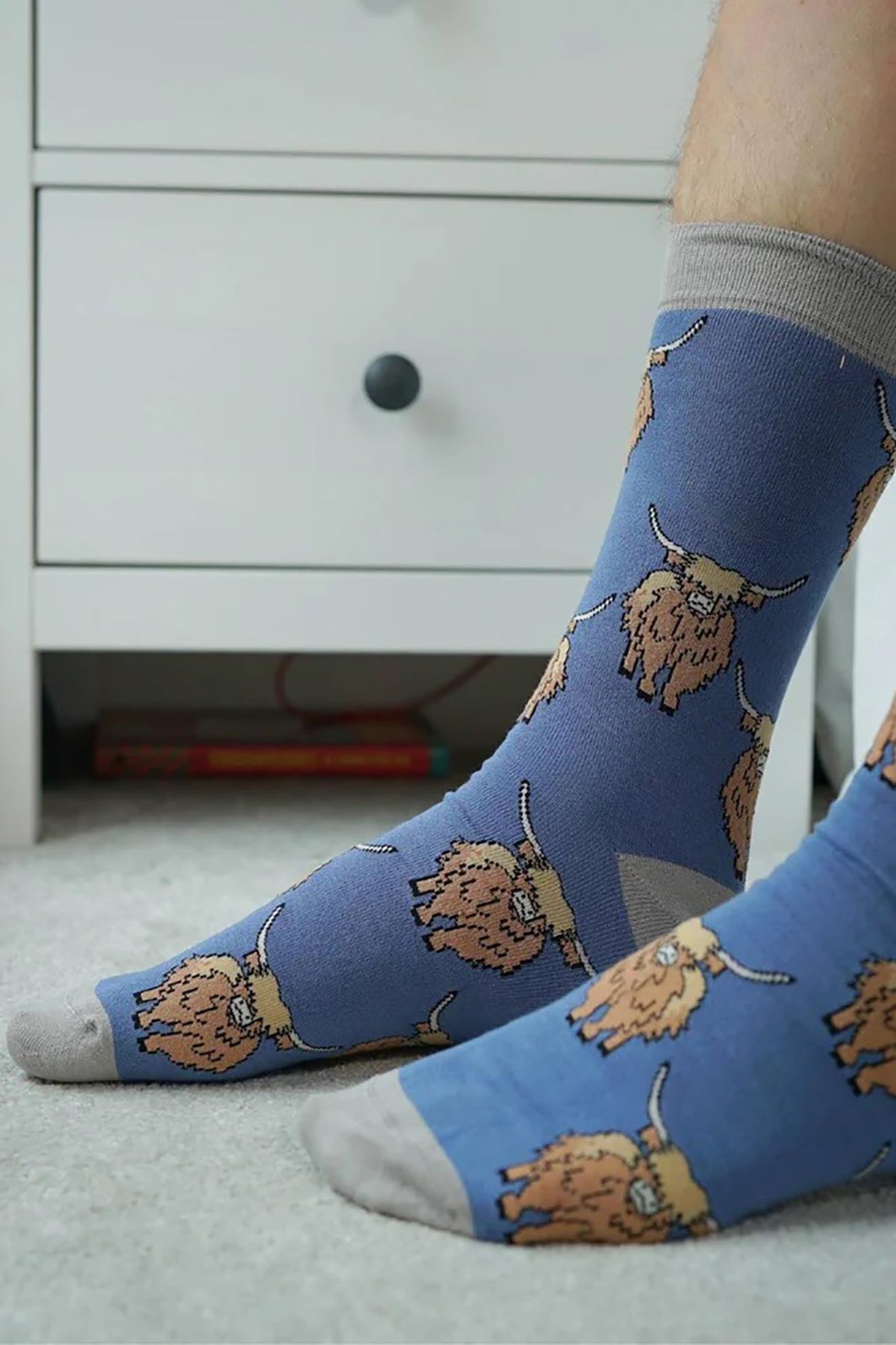 Blue bamboo crew socks with highland cow pattern and grey cuffs worn at home — Urban Wild