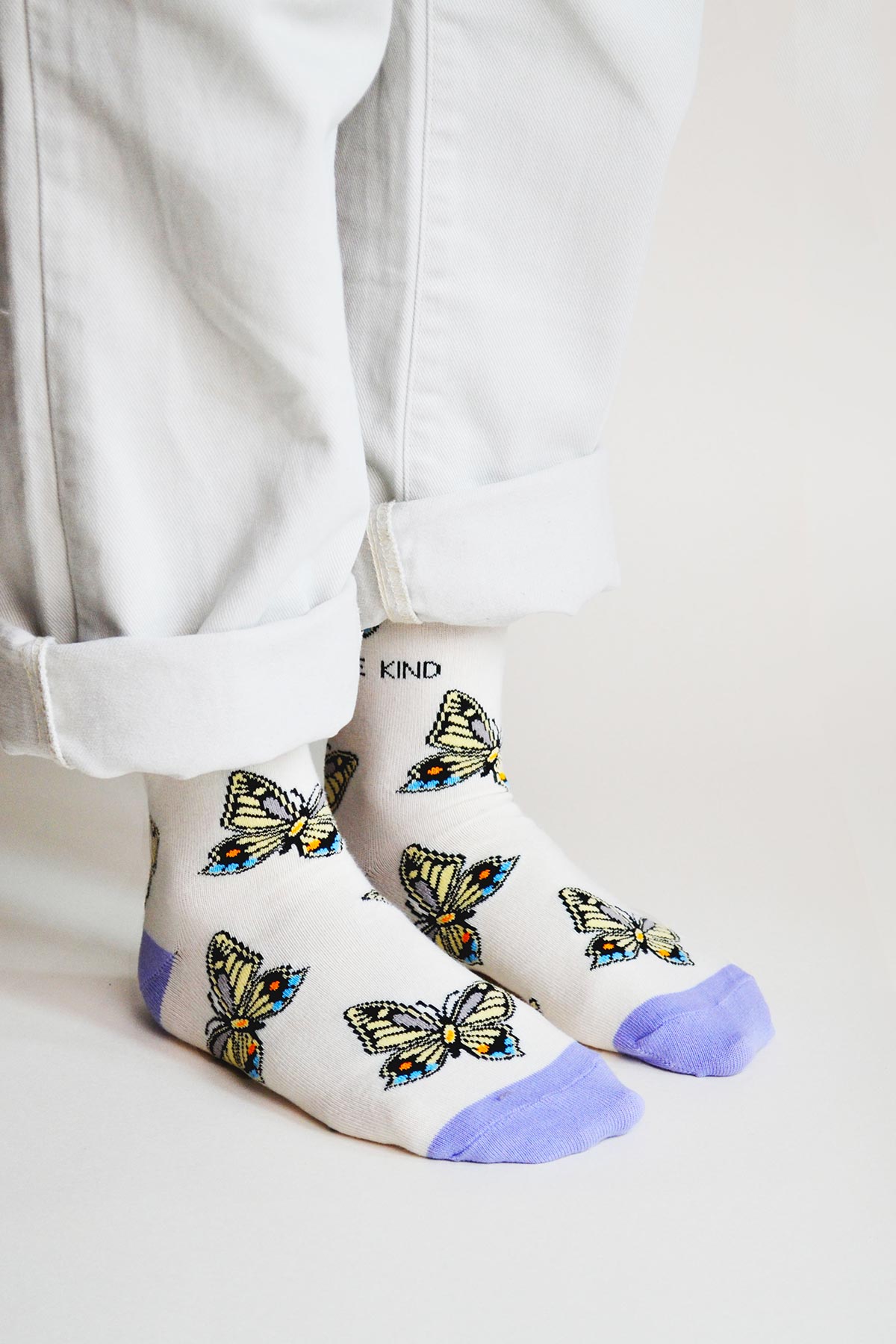 Model wearing cream and purple butterfly print bamboo crew socks with white jeans — Urban Wild