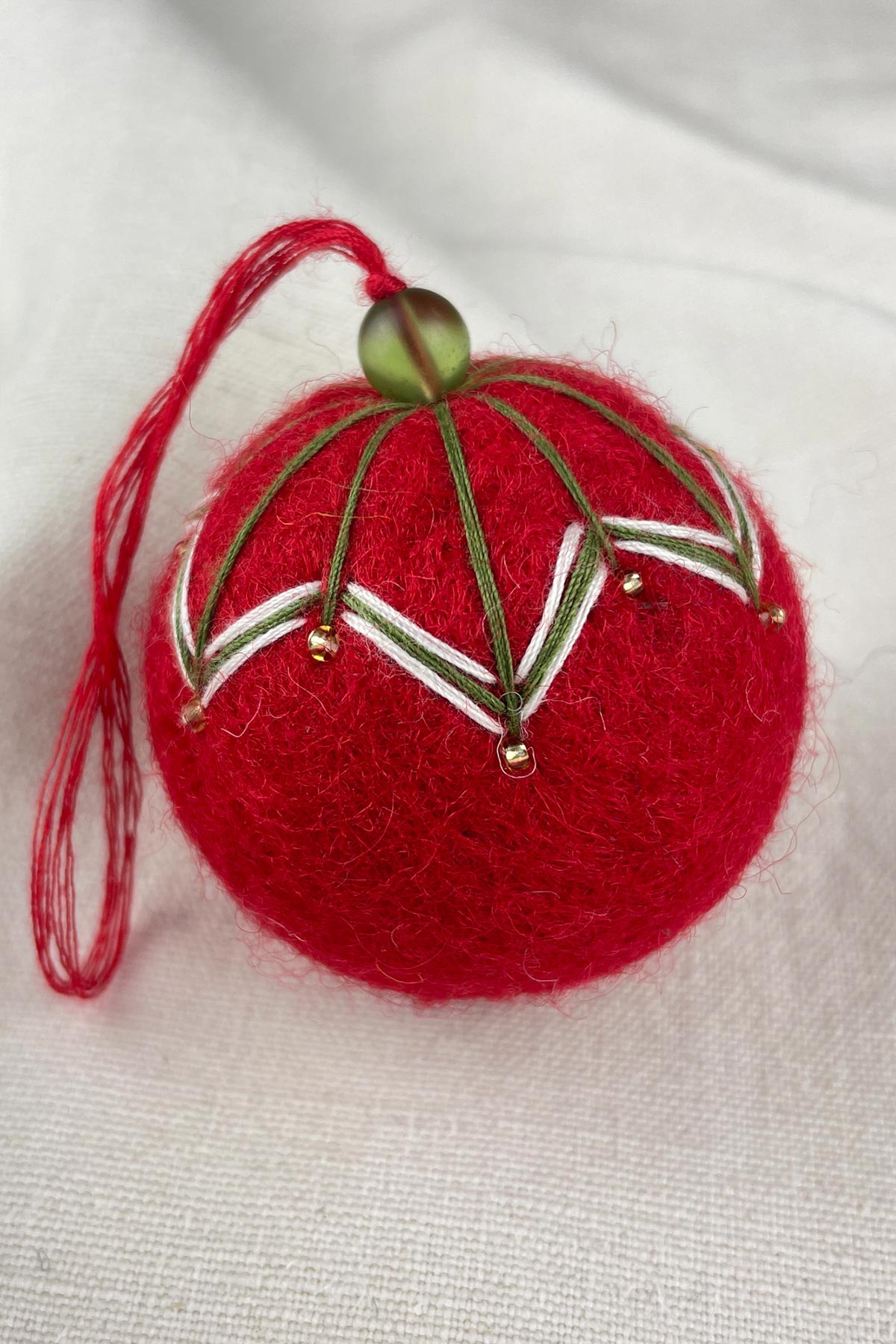 Close-up of beads on felt bauble in berry red