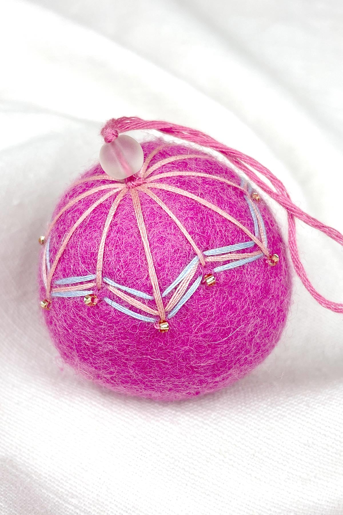 Close-up of beads on felt bauble in orange mango hibiscus pink