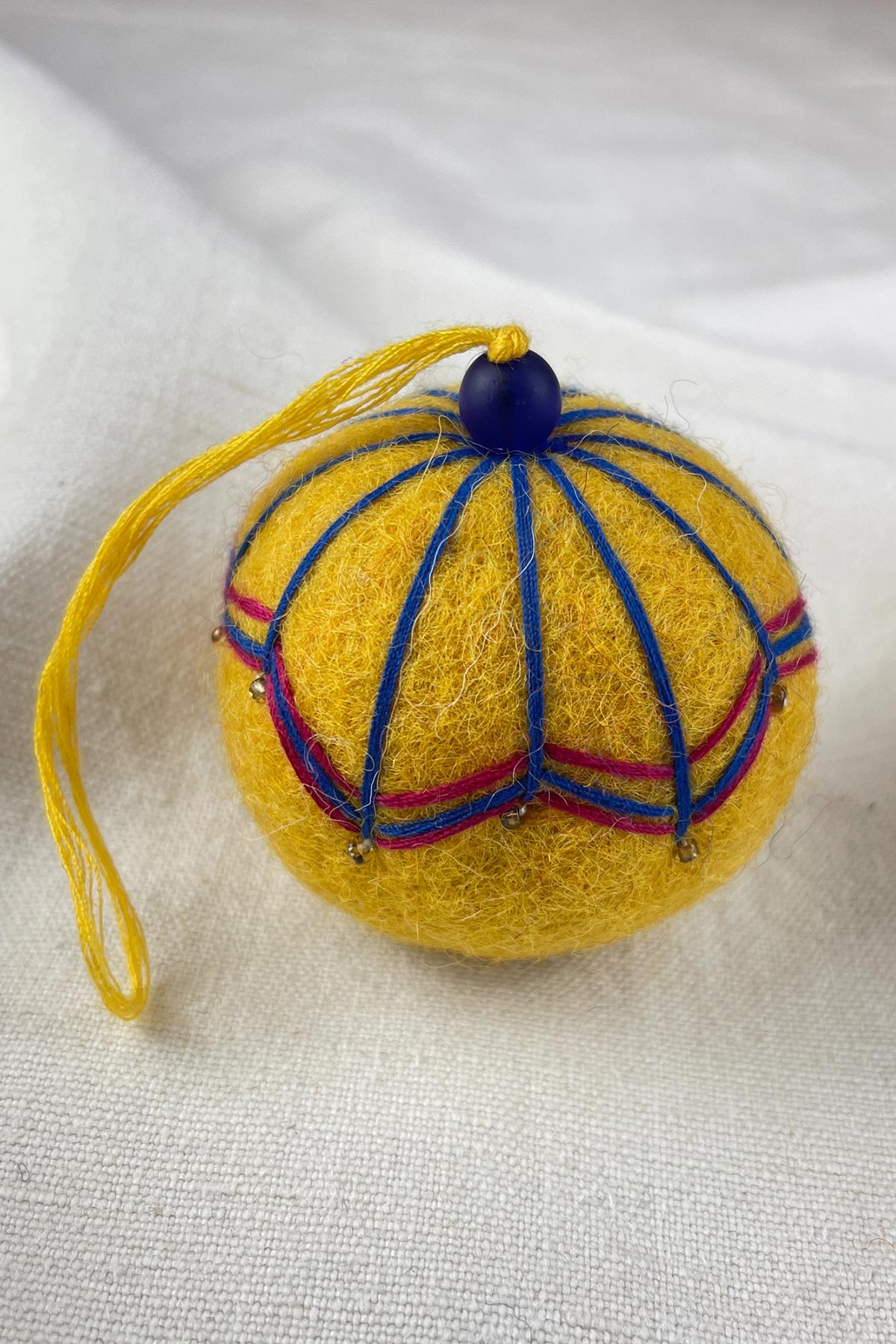 Close-up of beads on felt bauble in mustard yellow