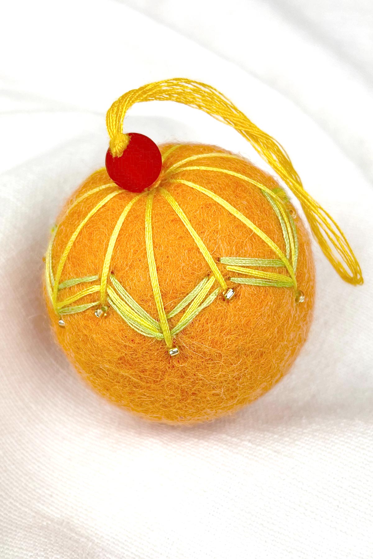 Close-up of beads on felt bauble in orange mango