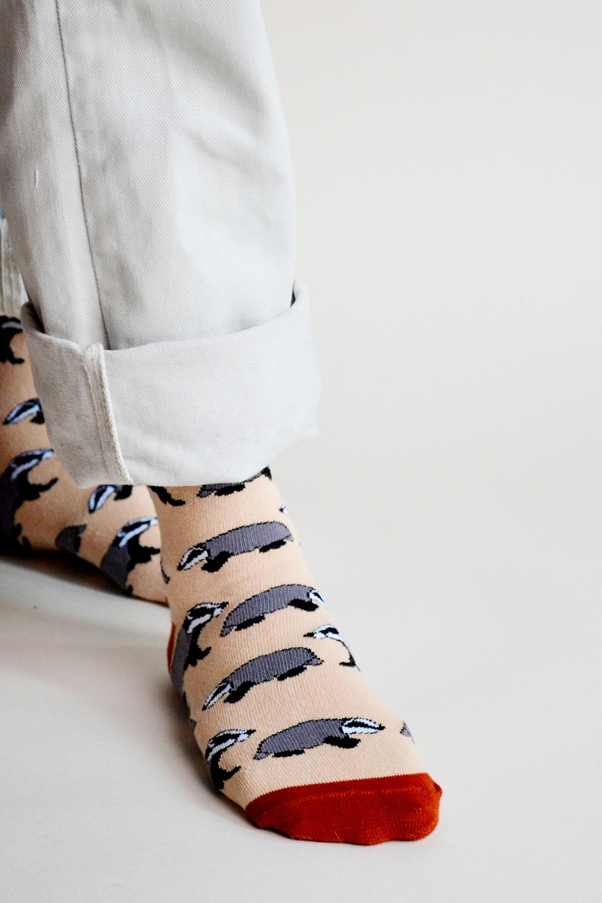 Beige bamboo socks with grey badgers and rust toe, side view on feet — Urban Wild