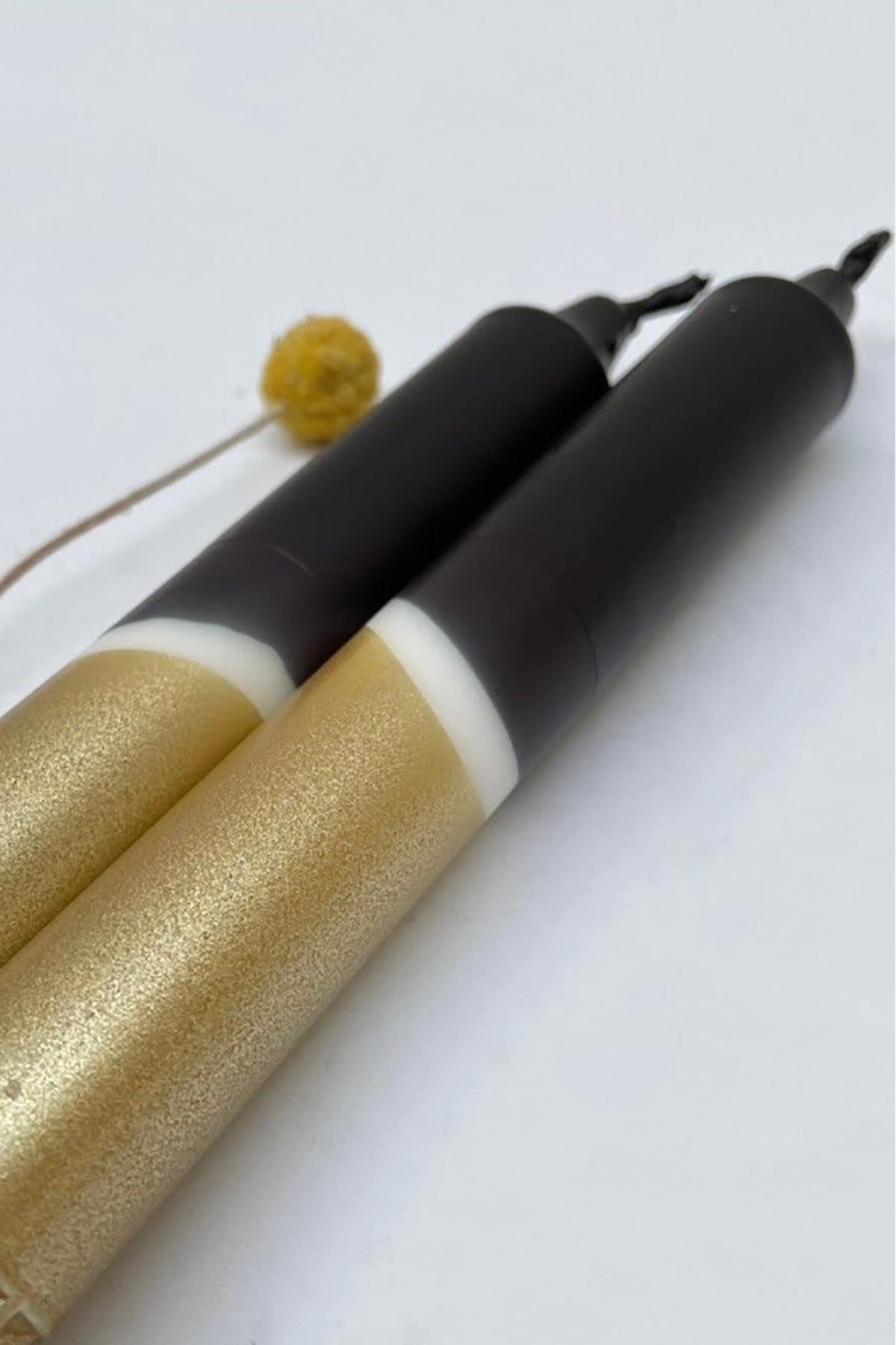 Pair of black gold taper candles displayed on mantelpiece — Urban Wild