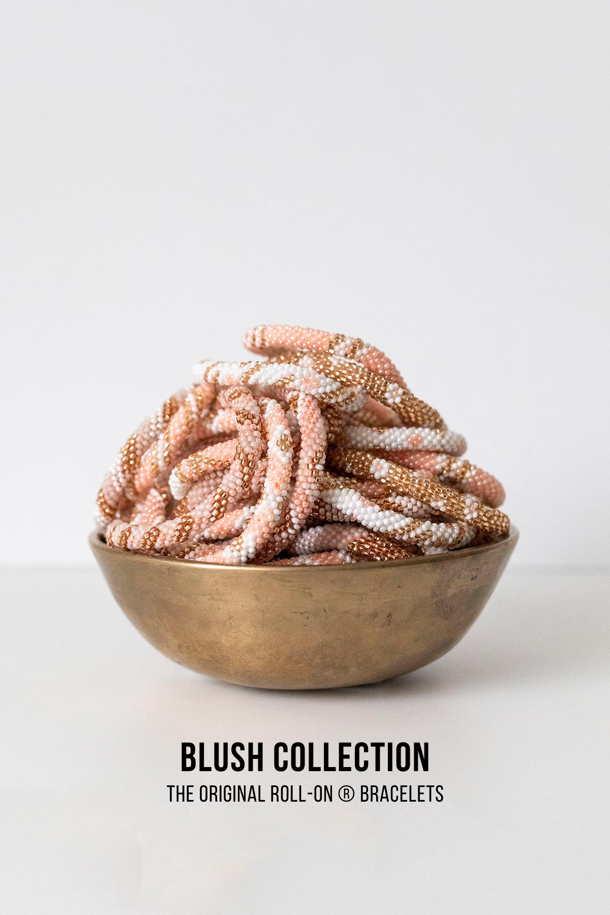 Blush pink and gold beaded Roll-On bracelets in a brass bowl — Urban Wild
