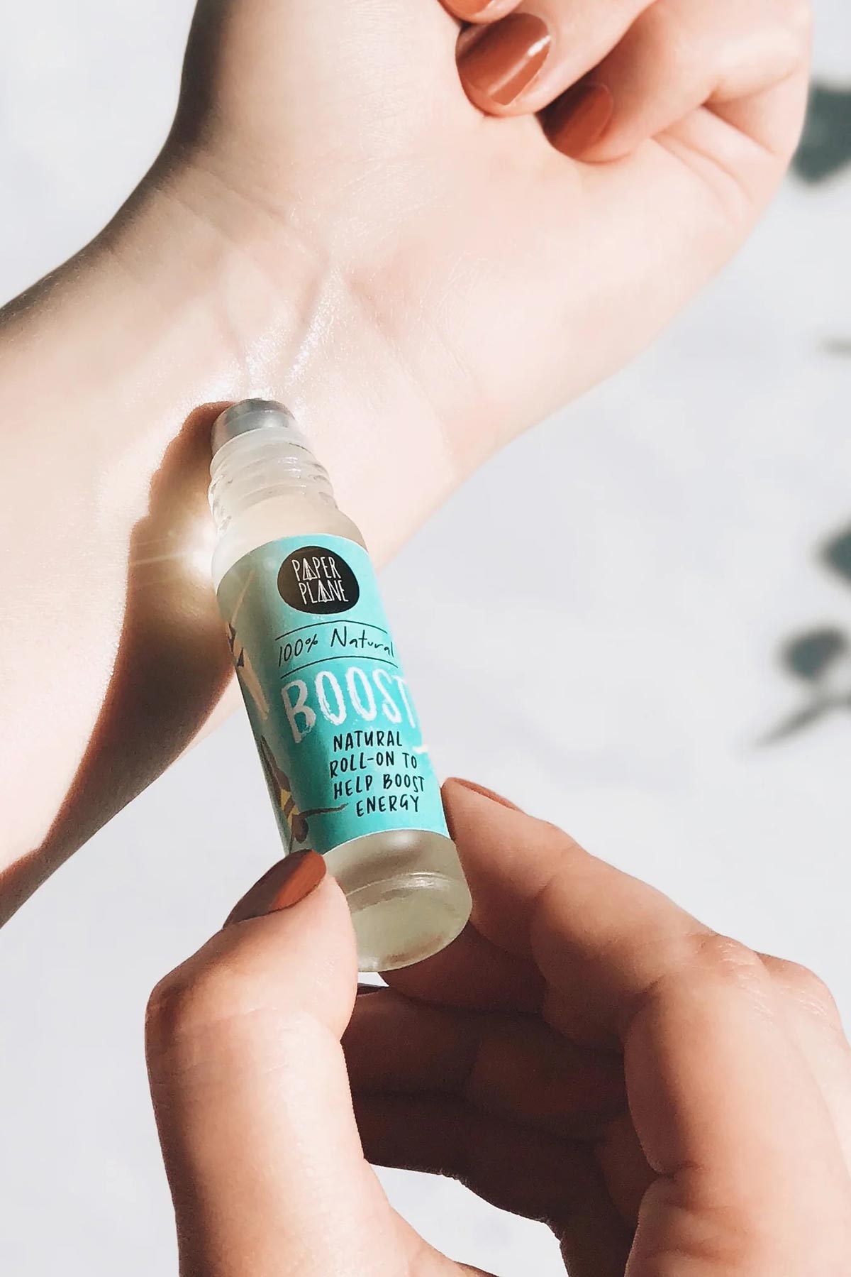 Hand applying Paper Plane Boost natural energy roller oil to wrist pulse point — Urban Wild