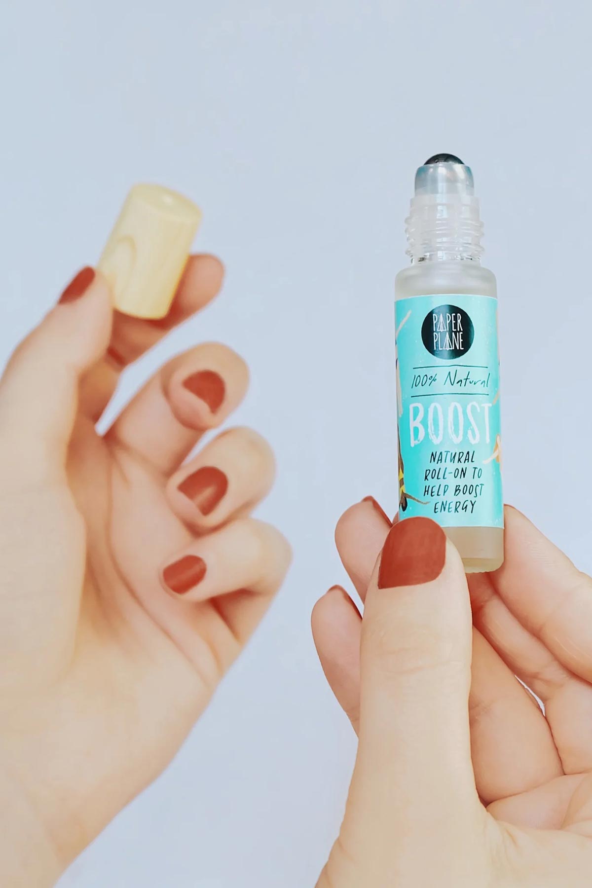Hands holding open Boost natural energy roller oil bottle with wooden cap — Urban Wild