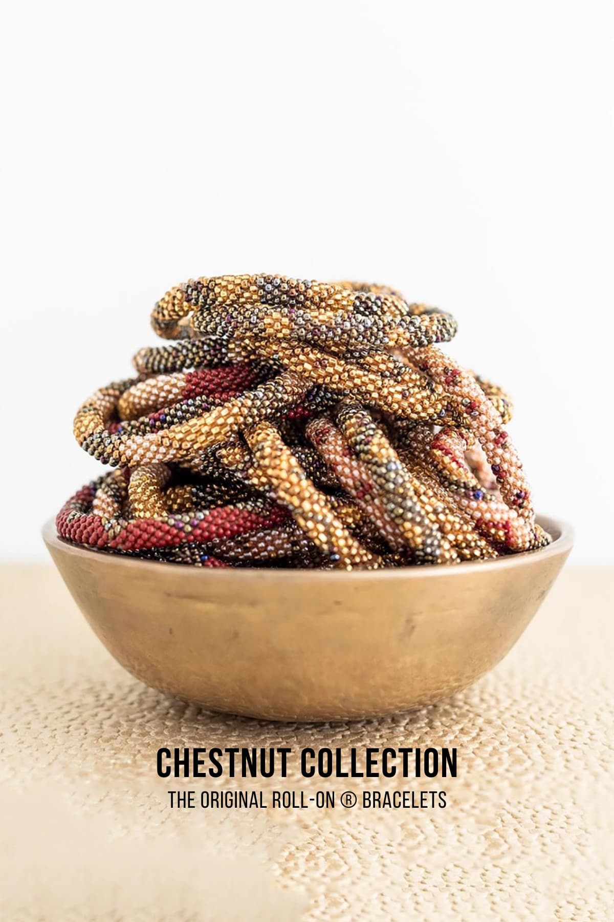 Chestnut beaded Roll-On bracelets in burgundy and gold piled in brass bowl — Urban Wild