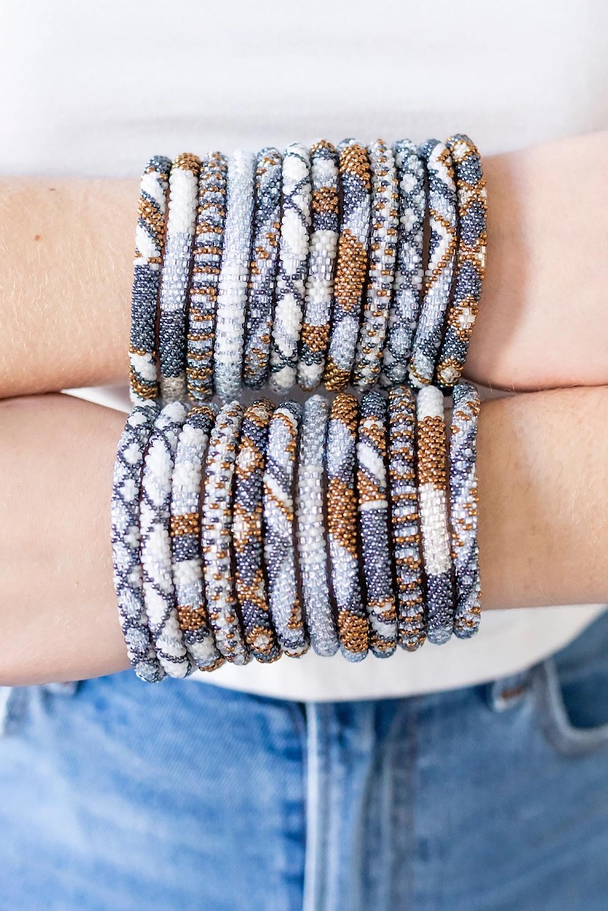 Stack of Elemental beaded Roll-On bracelets worn on wrists with denim — Urban Wild