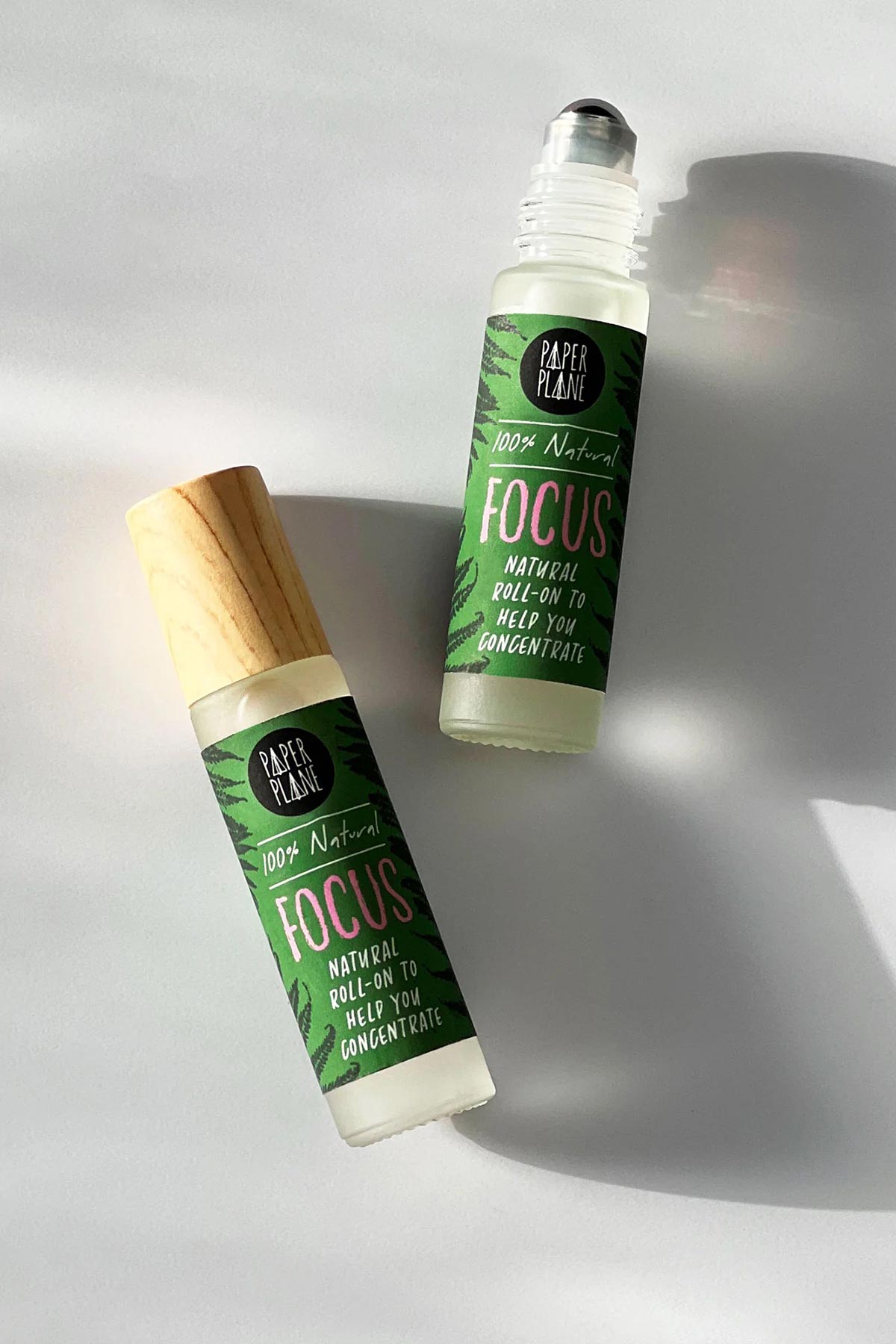 Two Focus natural roller oil bottles with green fern label flat lay — Urban Wild