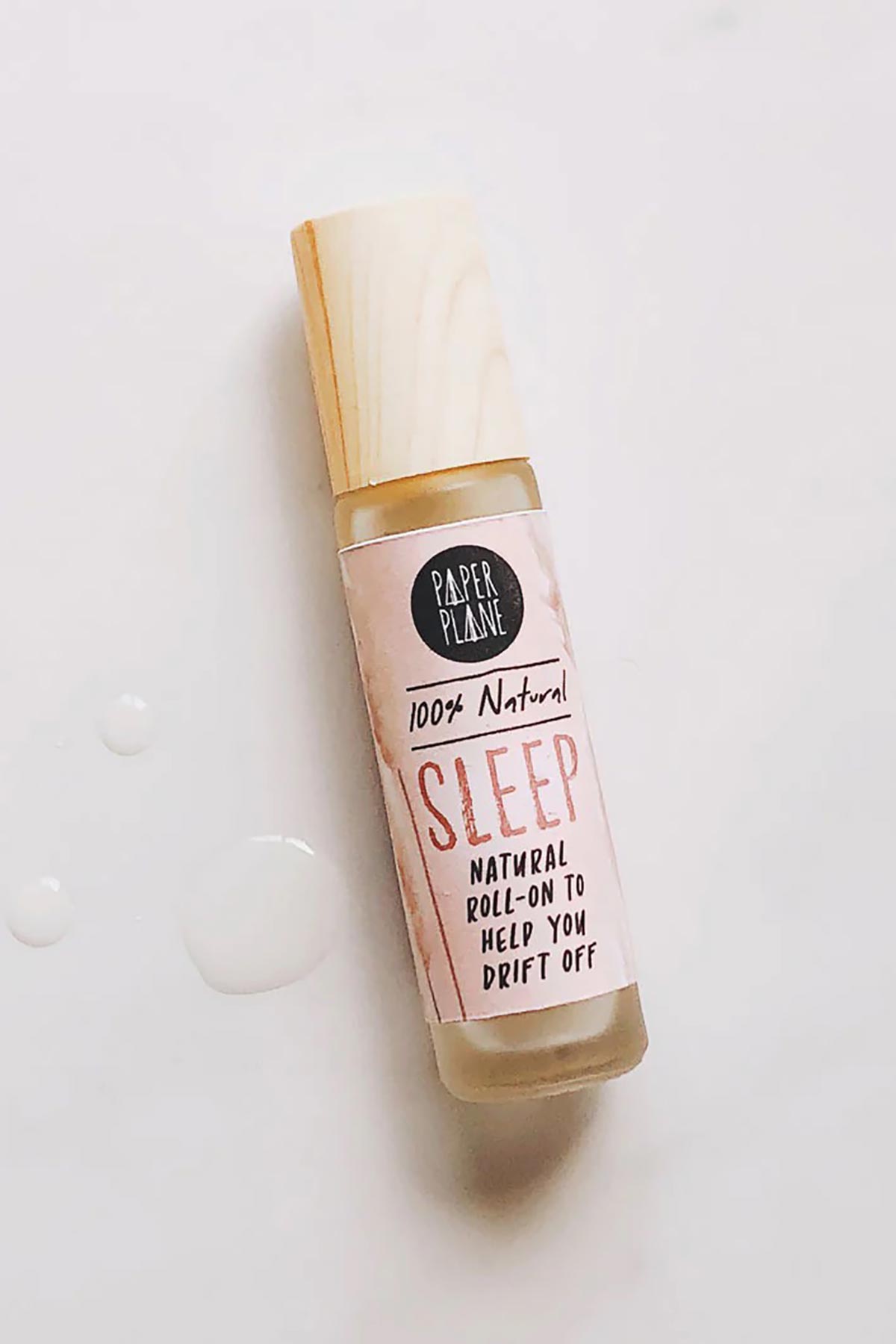 Sleep roller oil bottle laid flat on white surface with water droplets — Urban Wild